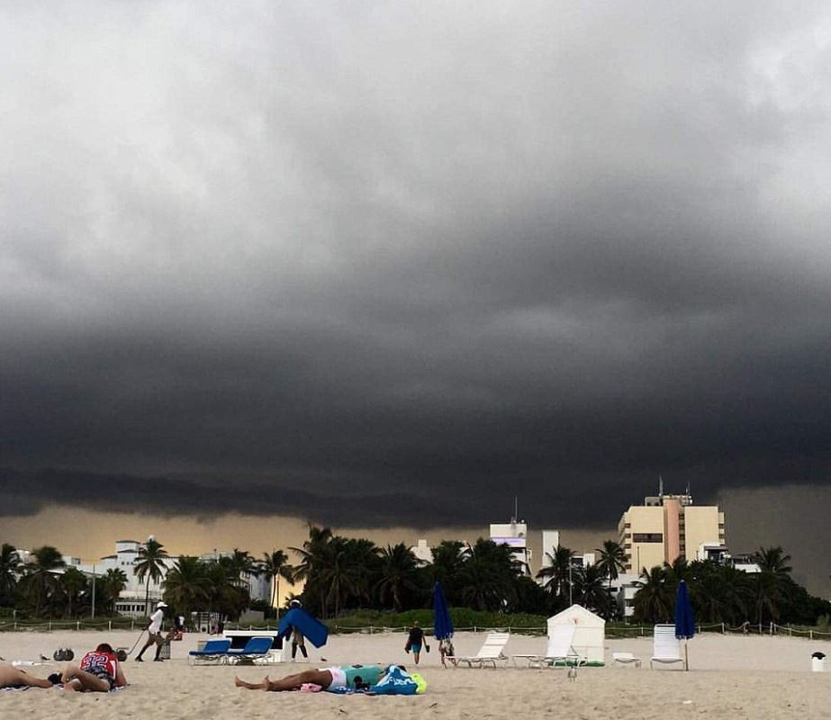 Sunbathers lie on the sand in Miami despite the ominous clouds gathering in the distance