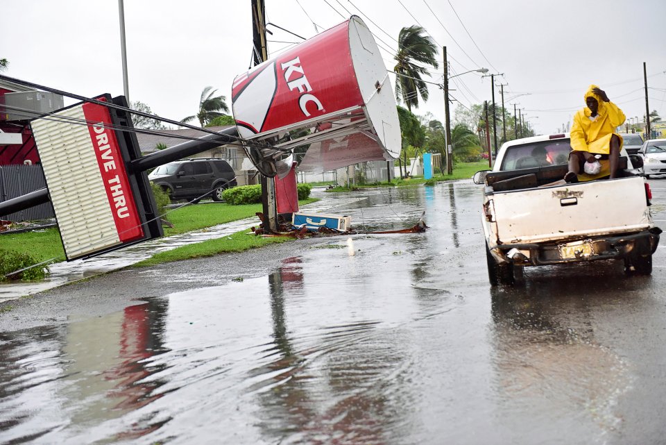 A KFC sign damaged by Hurricane Matthew is supported by utility lines on Carmichael Road in Nassau