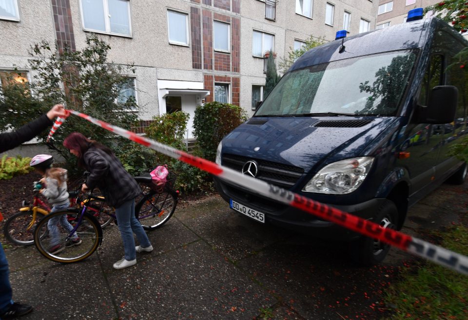  Residents pass under a police line as a vehicle of the German Criminal Police is seen in the Paunsdorf district in Leipzig