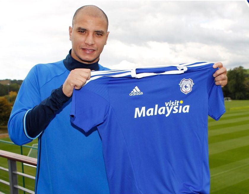 Marouane Chamakh holds the Cardiff shirt after singing - but his hair was the bigger talking point