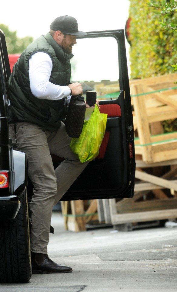  Tyson Fury holds a washbag and a mobile phone as he steps out of his jeep