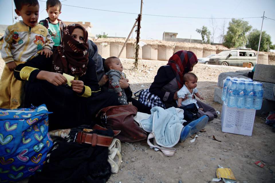 Displaced Iraqi women, who fled the Islamic State group held Hawijah area, sit with their children before being screened at the Dibis checkpoint northwest of the northern Iraqi city of Kirkuk