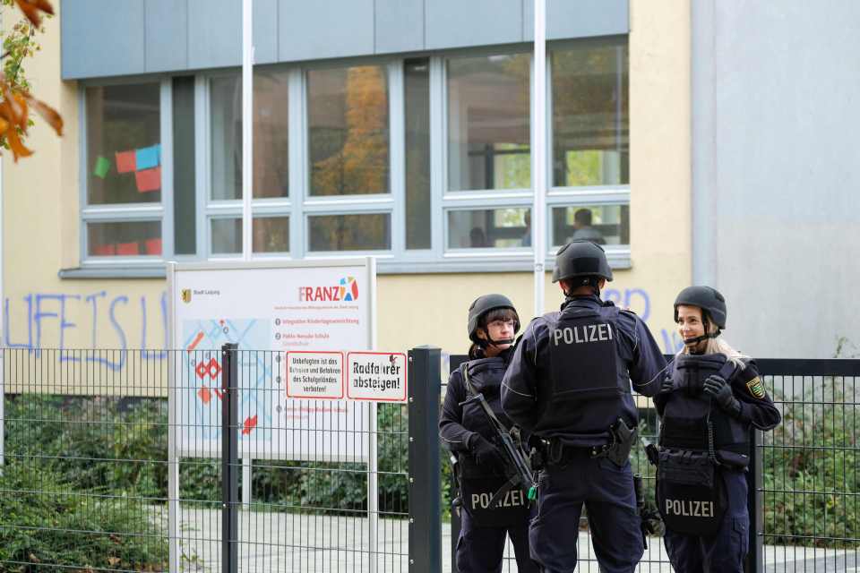  A group of police officers stand guard outside one of the schools threatened via email