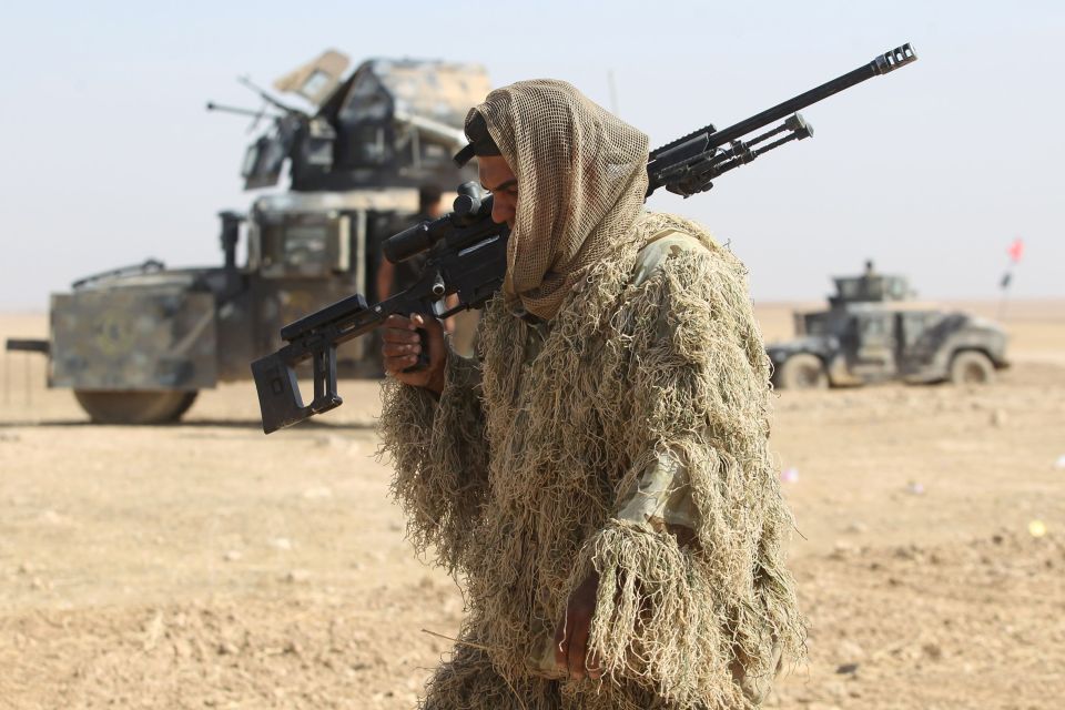 A camouflaged Iraqi armed forces member walks through a recently-liberated village