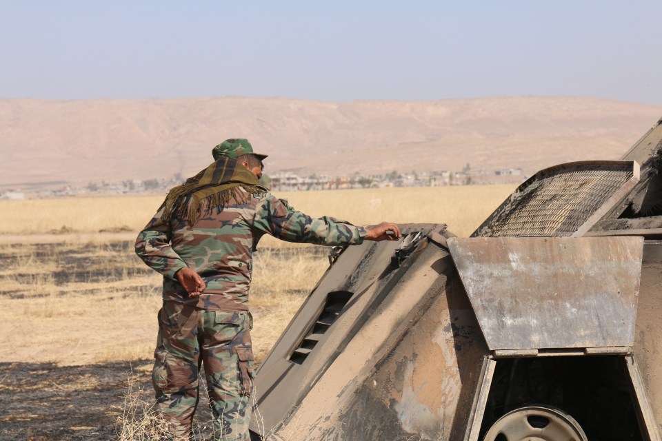 A fighter inspects the burned out vehicle