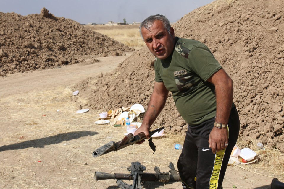 A fighter collects weapons claimed after last night's clash with ISIS forces near Mosul