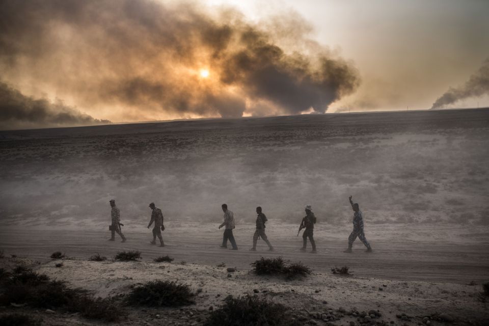  A group of soldiers march through the scarred and war-torn landscape near Mosul