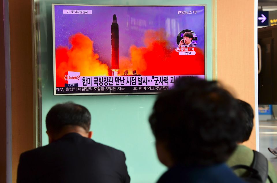 People watch a television news report showing North Korea's missile launch at a railway station in Seoul, South Korea