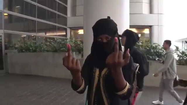  The unidentified woman flips the bird at the photographer after declaring "f*** America"