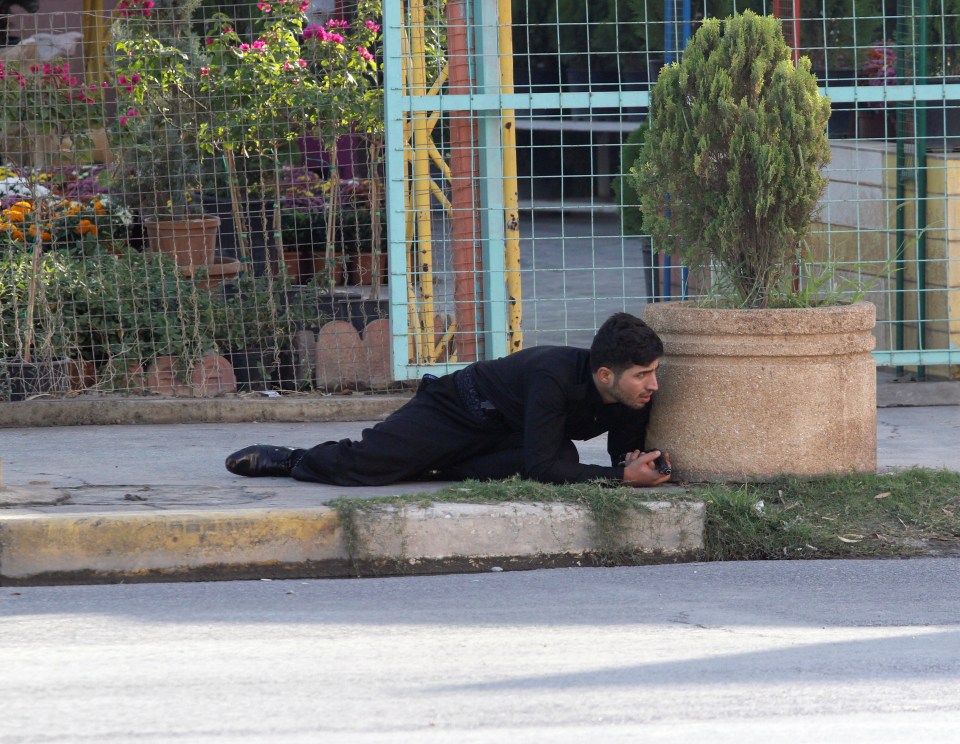  A Kurdish security personnel takes cover at a site of an attack by Islamic State militants in Kirkuk