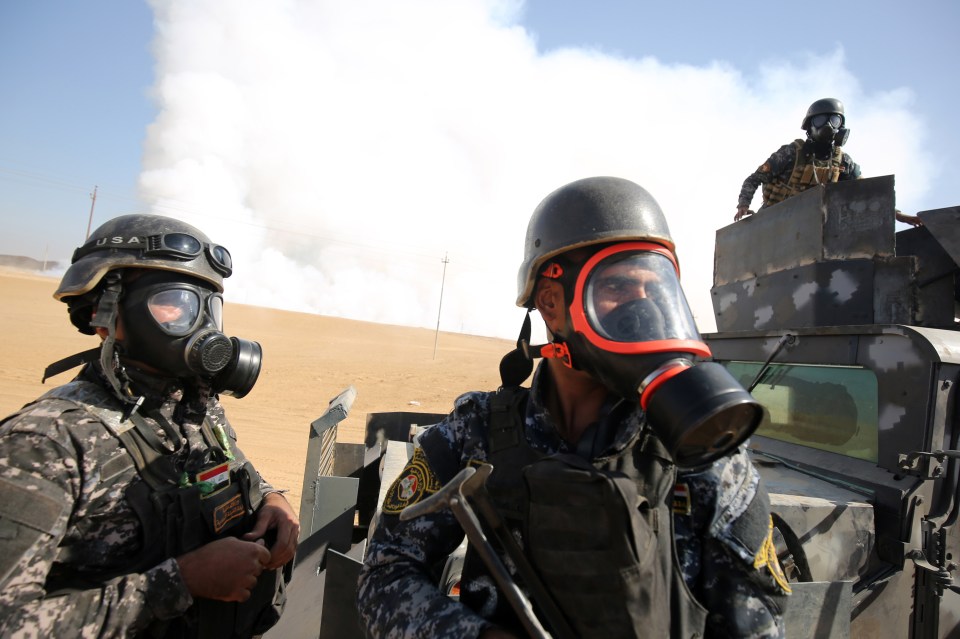  Iraqi forces wear protective masks after winds brought fumes from a nearby sulfur plant set alight by Islamic State militants, at south of Mosul in Qayyara, Iraq, October 22