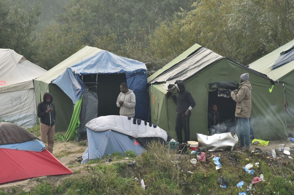  Migrants gather by their tents as they prepare to leave the Jungle