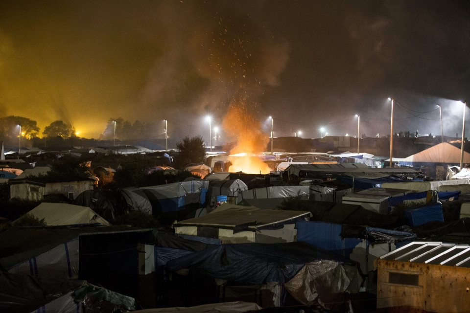  A large fire lit with bits and pieces from the abandoned tents and shacks burns in the makeshift camp