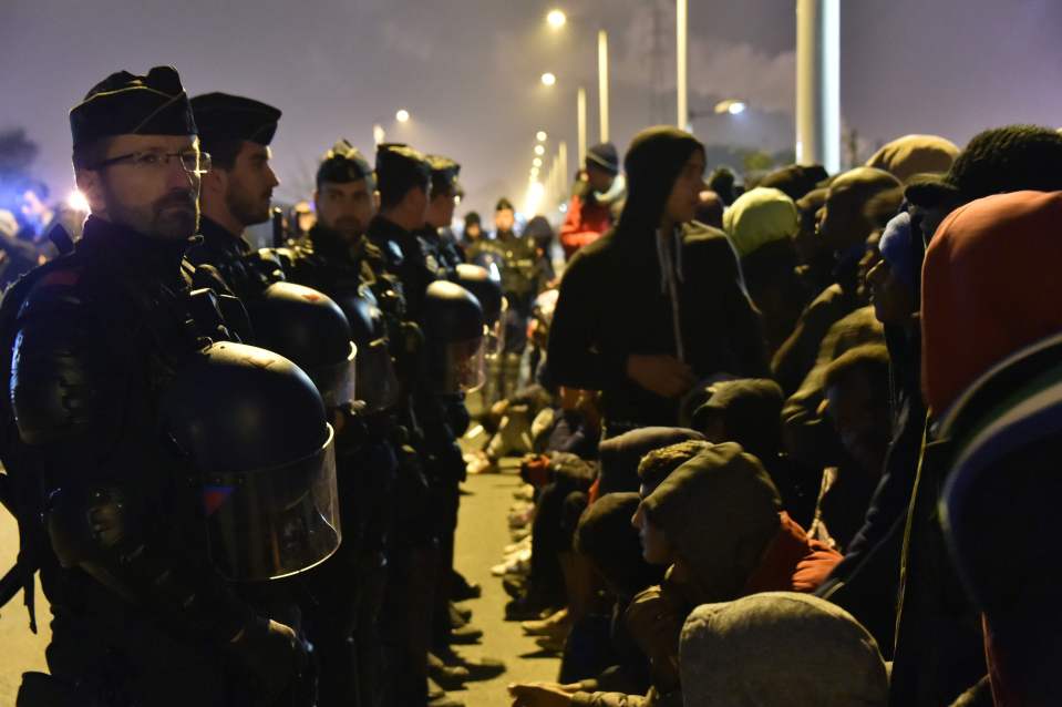 Lines of police flank the groups of migrants gathering to be registered as the camp is demolished