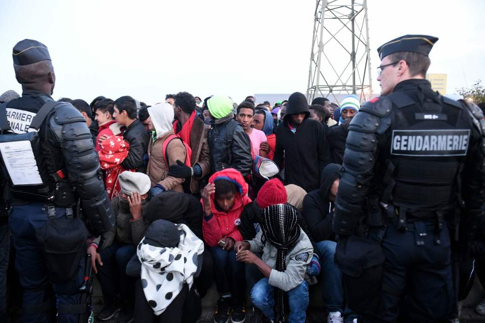 French anti-riot policemen stand guard a gathering of migrants 