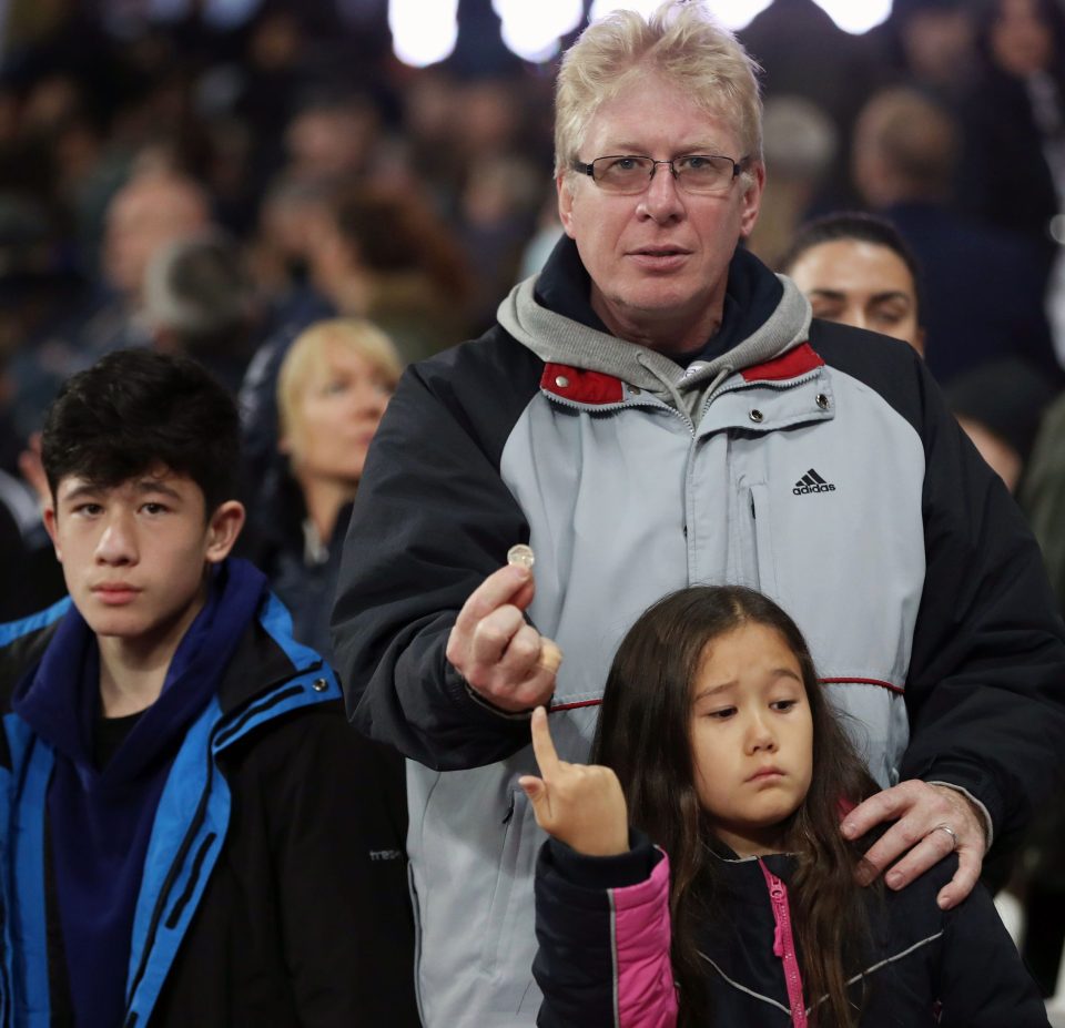  A Chelsea fan with his family holds up a coin that was thrown at them