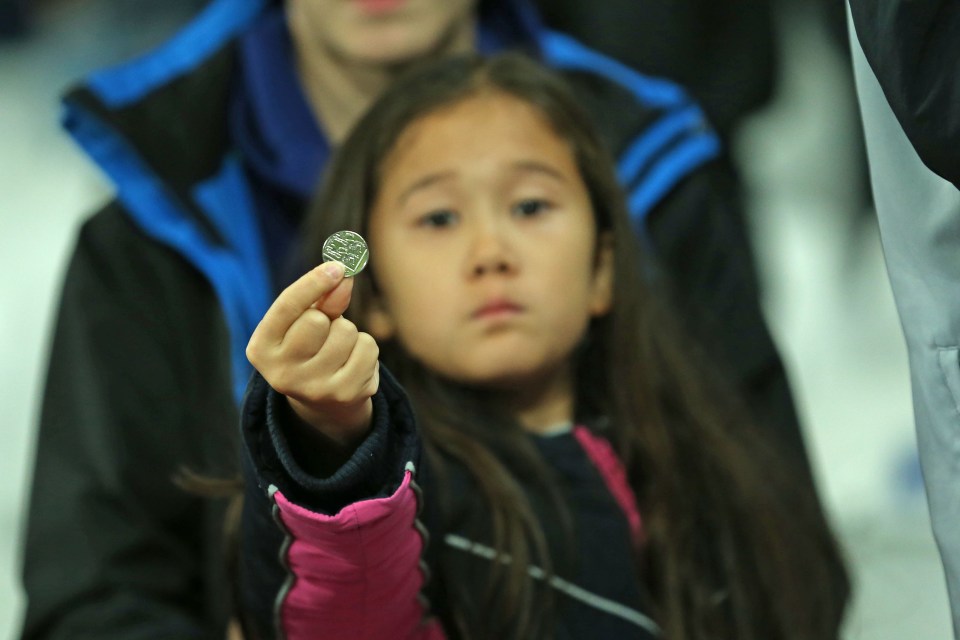  An 8-year-old girl holds up a coin thrown by West Ham fans at the London Stadium