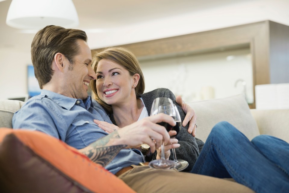 Couple drinking wine on living room sofa