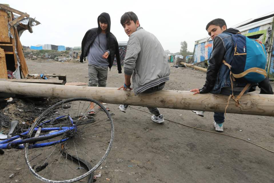  Young people sit among debris in the remains of the Jungle in Calais today