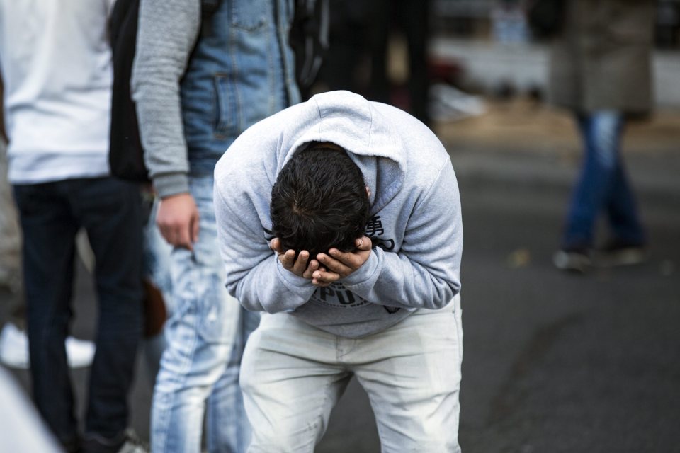  An Afghani migrant reacts after being pepper sprayed by riot cops