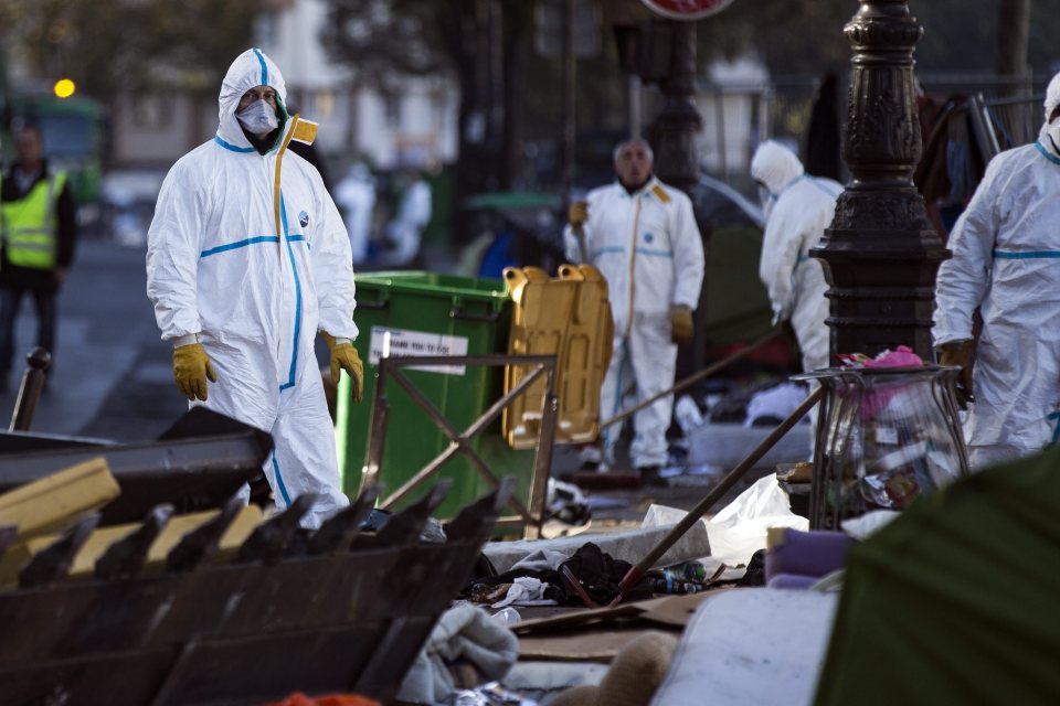  Workers clean the remains of the Afghani makeshift camp in Paris today