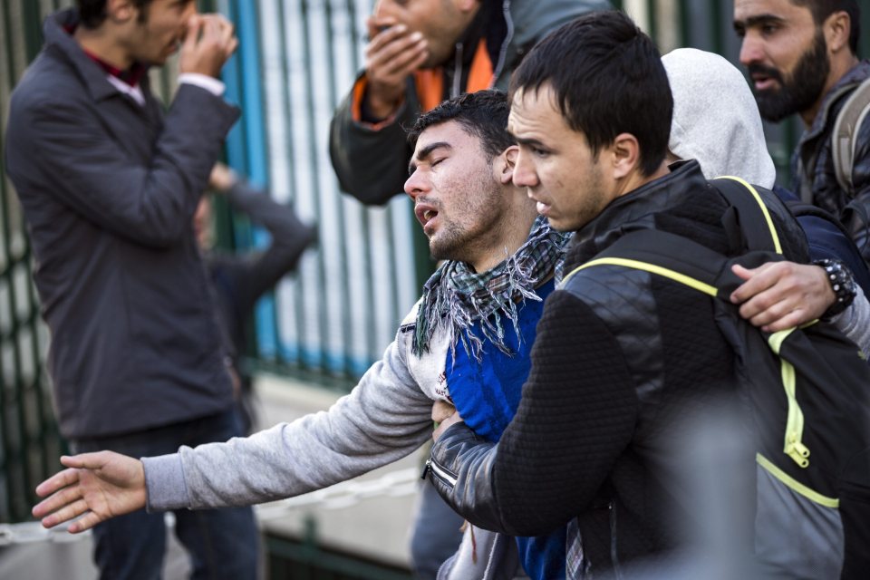  An Afghani migrant is carried by a friend after being pepper sprayed by cops