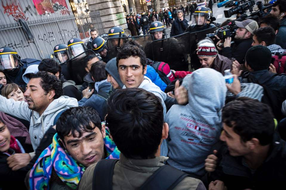  A line of riot police restrains migrants in a street of Paris today