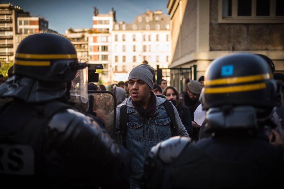  A migrant faces French riot police near the Stalingrad metro station today