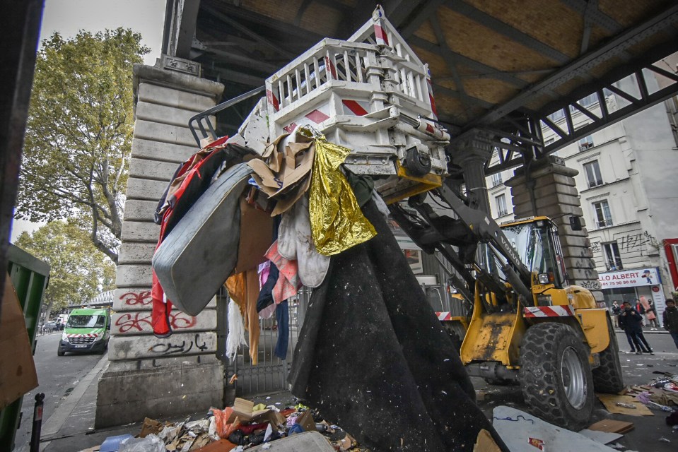  A bulldozer clears away rubbish and makeshift shelters