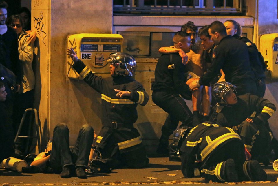  Fire crews tend to an injured victim outside the Bataclan