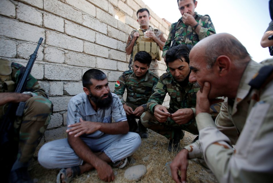  Kurdish Peshmerga fighters question a man north of Mosul