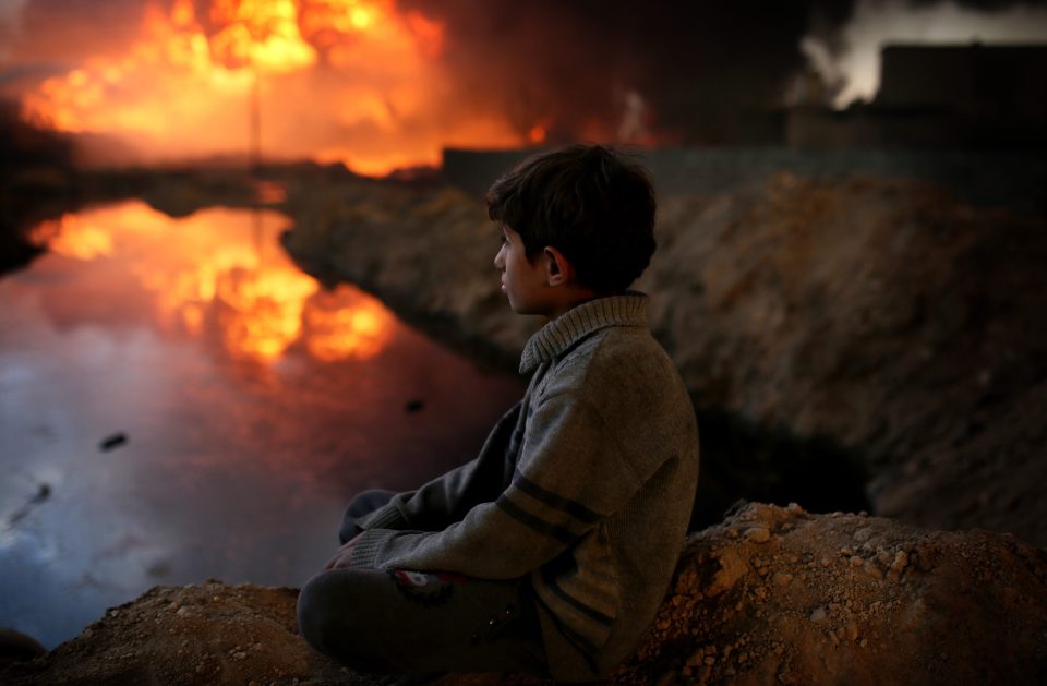  A horrified child watches after desperate terrorists destroyed oil fields while they retreated