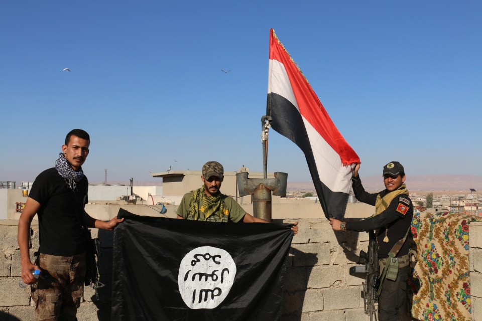  Soldiers pose with an ISIS flag captured during the battle