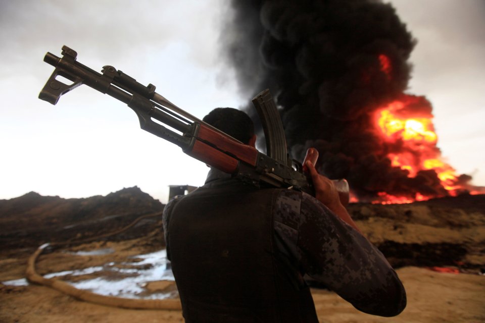  A member of the Iraqi forces watches an oil well burn as ISIS retreats from Mosul