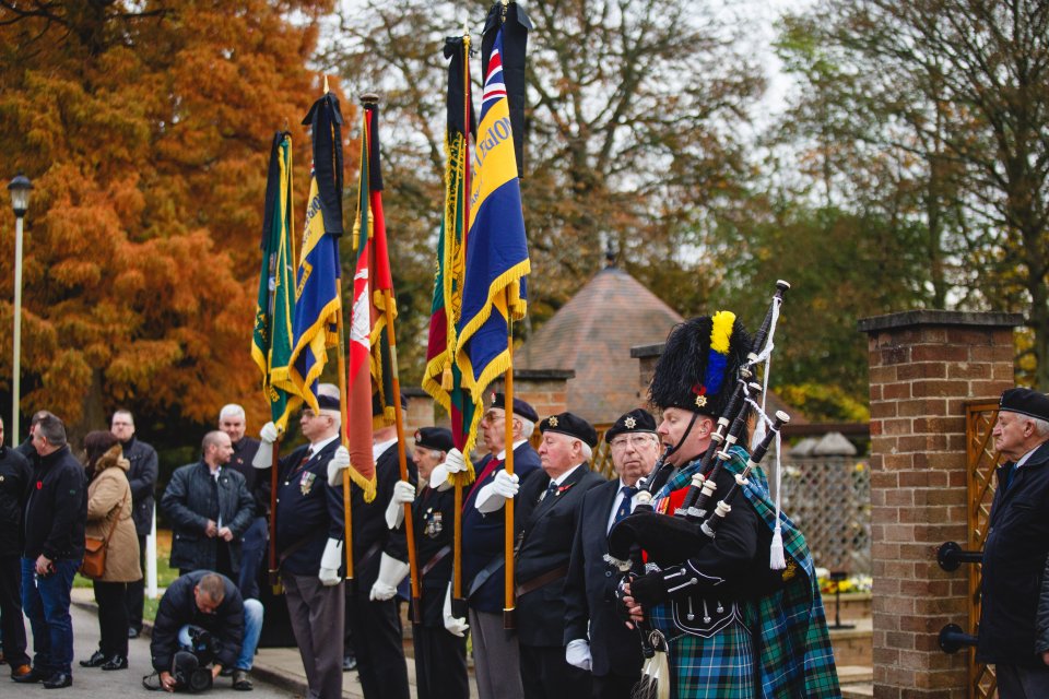 Soldiers and ex-servicemen look on as bagpipers play outside 