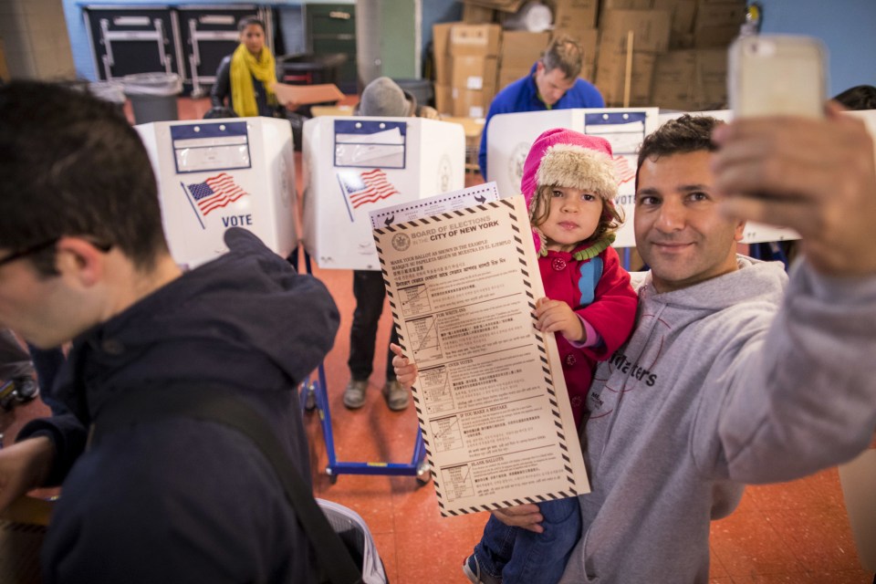 A man takes a selfie with his child as he waits to vote 