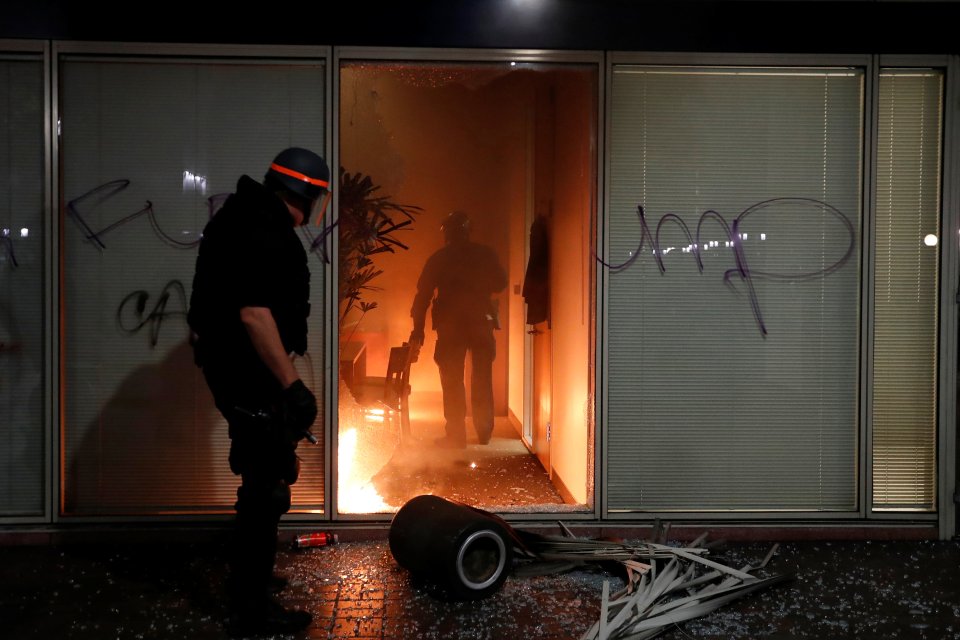  A police officer checks an office set aflame by demonstrators