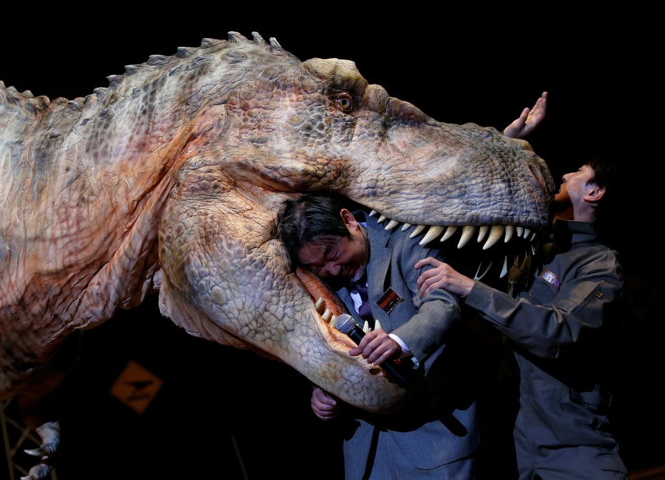 The human-controlled T-rex appears to bite the head of a man