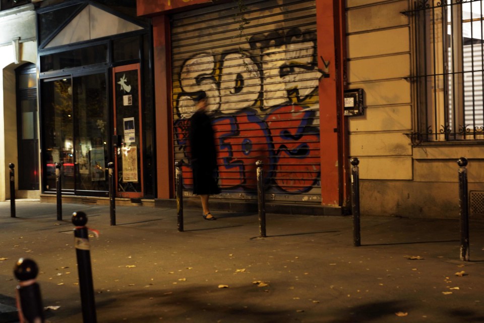  A year after the mass murder a woman can be seen walking past the same shot where one of the terror's most enduring images was captured