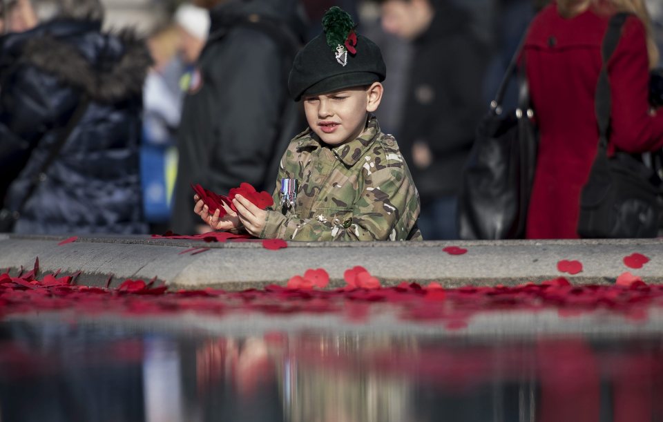  A child inspects the poppies scattered in the fountains of Trafalgar Square