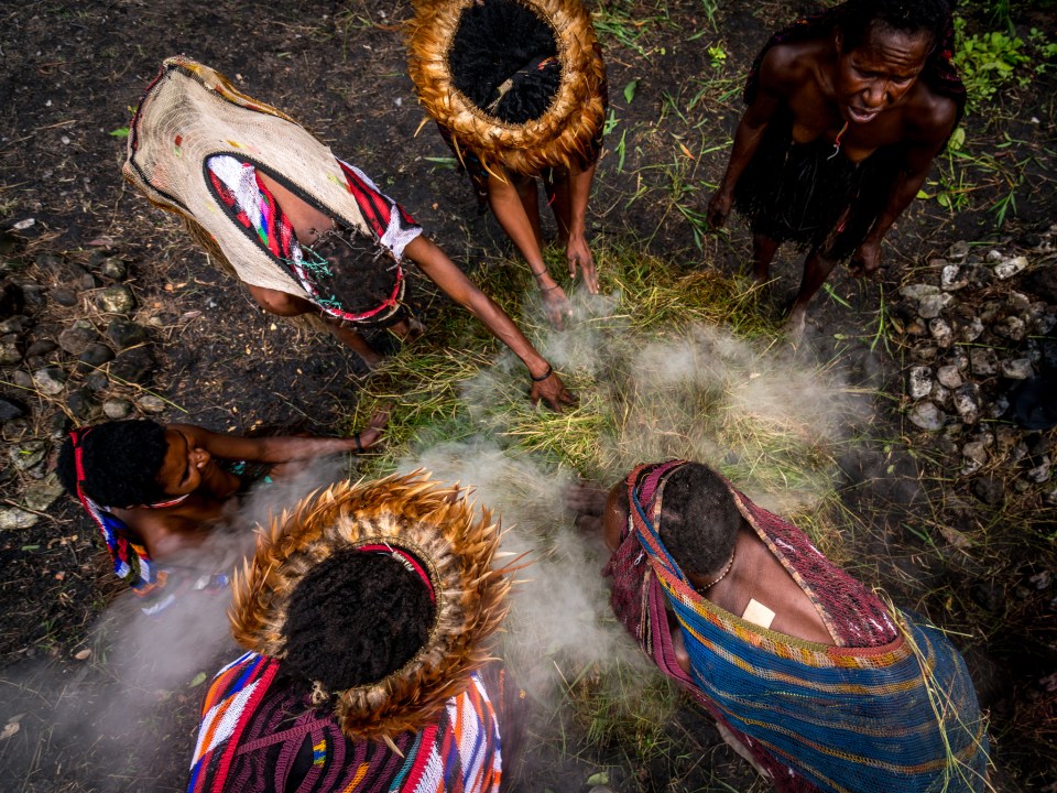 Dani tribeswomen using a traditional oven to cook food