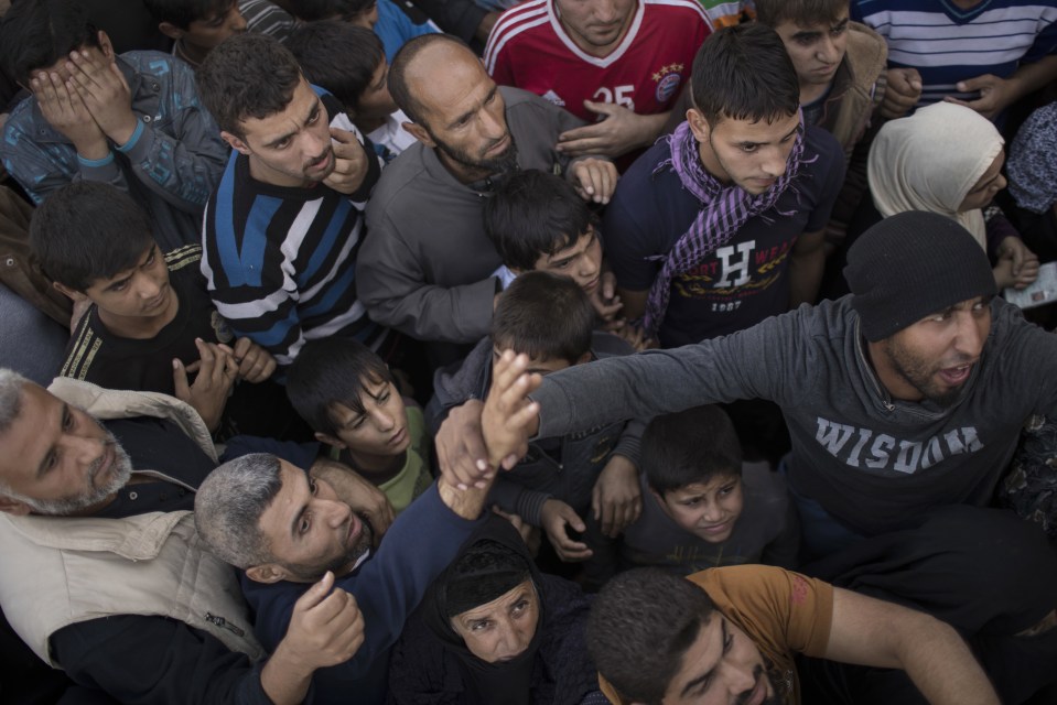  Residents gather to receive food supplies being distributed in Mosul