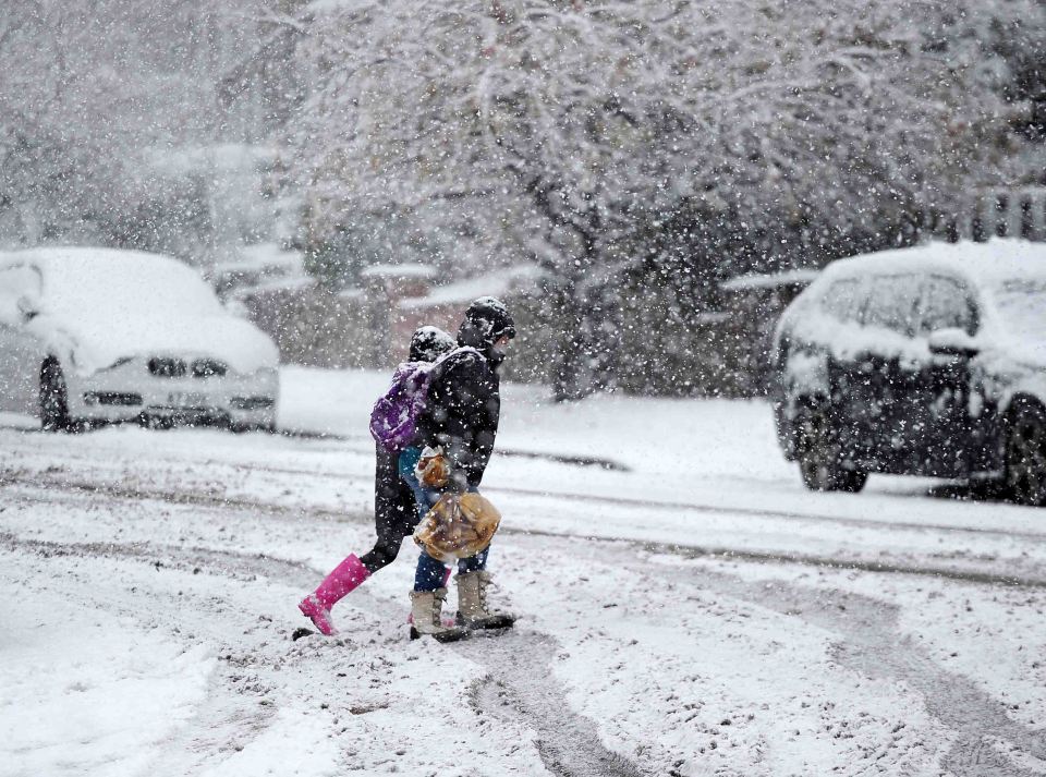 A family cross the snow covered road in Rochdale, Greater Manchester