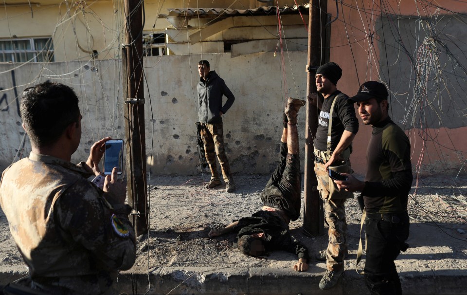  Iraqi special forces soldiers pose for a photograph next to the hanging body of an Isis fighter