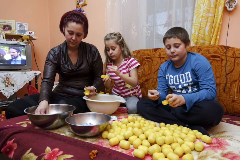 Hannah and Patrick at work helping mum Timea to put together the Kinder toys at their home in Romania