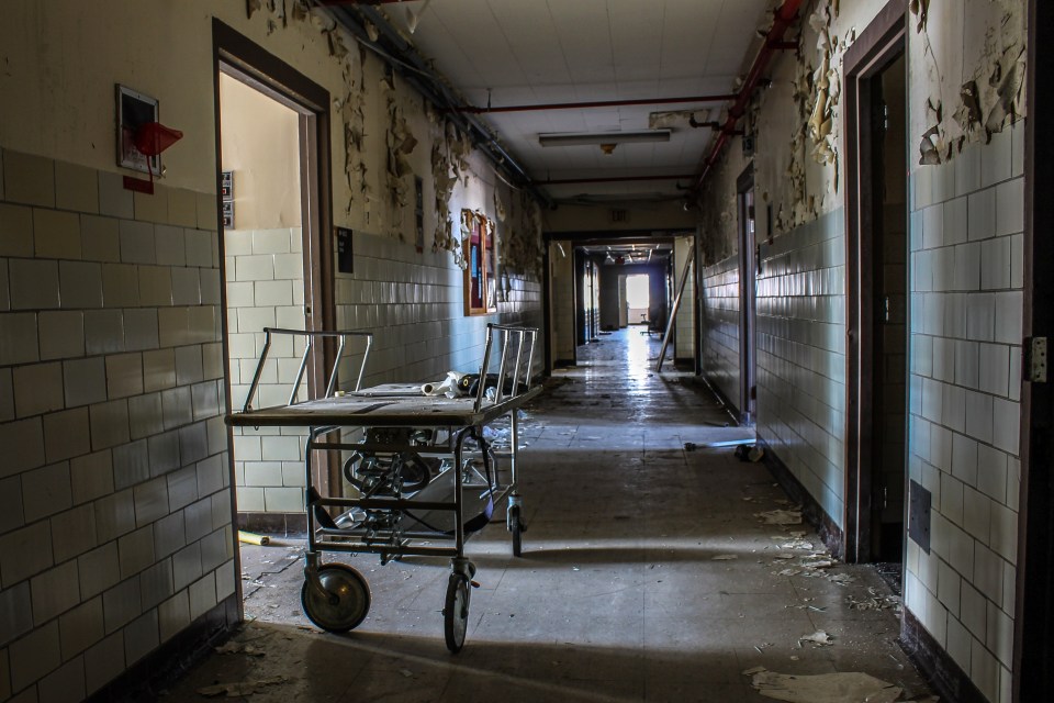 Rusty hospital beds lie abandoned in the hospital's decaying hallways