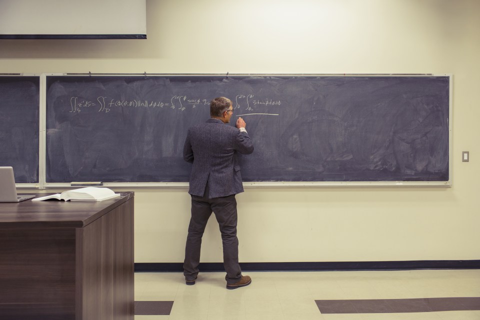 Caucasian teacher writing on chalkboard