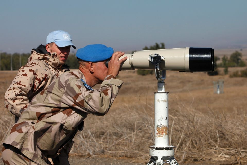  UN members look through binoculars to monitor the Israel-Syria border in the Israeli-annexed Golan Heights