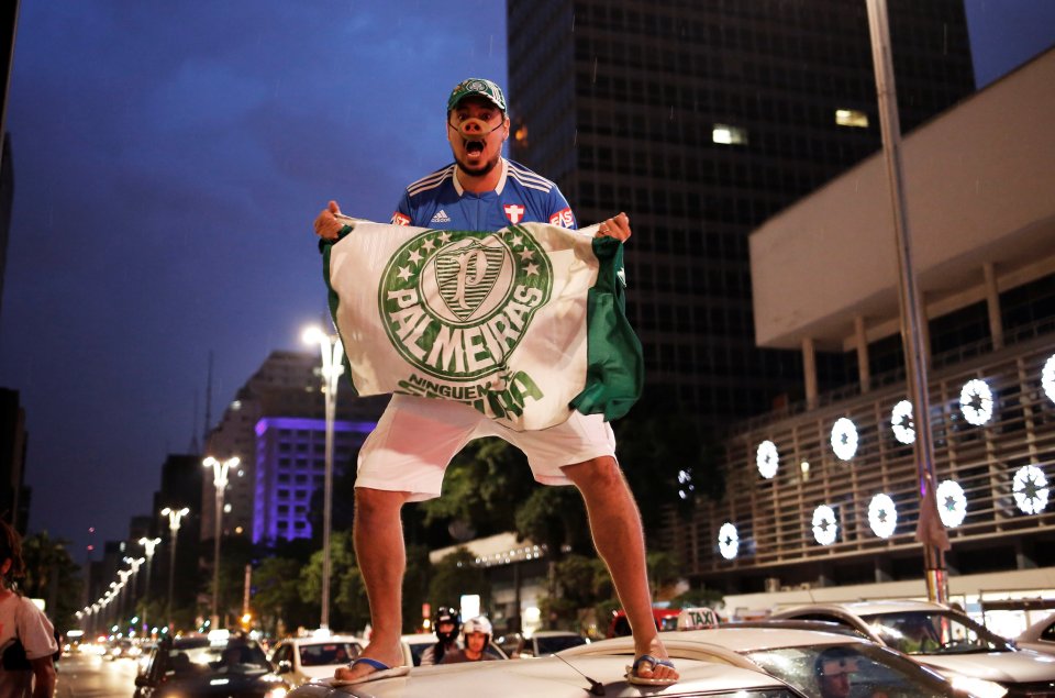 Palmeiras' fan celebrates their ninth Brazilian league title on the bonnet of his car at Paulista Avenue in Sao Paulo