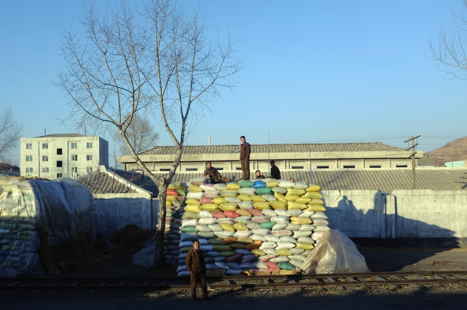  Soldiers gather on and around Chinese-labelled sacks of chicken feed in rural North Korea